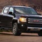 A black 2018 GMC Canyon, which is popular among used trucks in Atlanta, GA, is parked on dirt in front of hills.