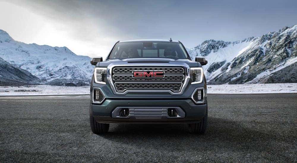 A gray 2019 GMC Sierra 1500 Denali is parked in front of snowy mountains and shown from the front.