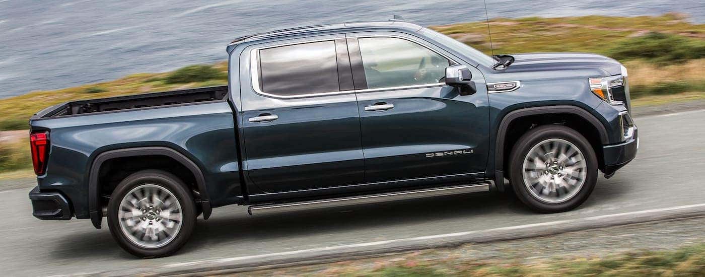 A blue/gray 2020 GMC Sierra 1500 Denali is driving on a highway in front of a river.