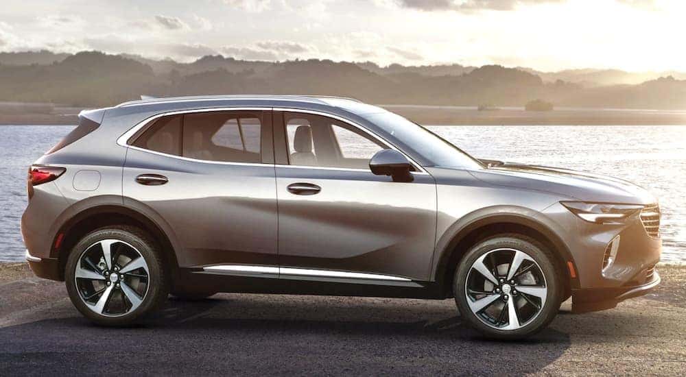 A grey 2021 Buick Envision is shown from the side in front of a bay at sunset.