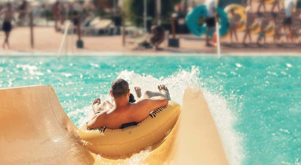 A man is shown going down the end of a waterslide from behind.