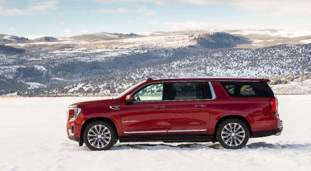 A red 2021 GMC Yukon XL Denali is shown from the side on a snowy mountain.
