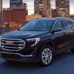 A black 2020 GMC Terrain SLE is on top of a parking garage overlooking the city.