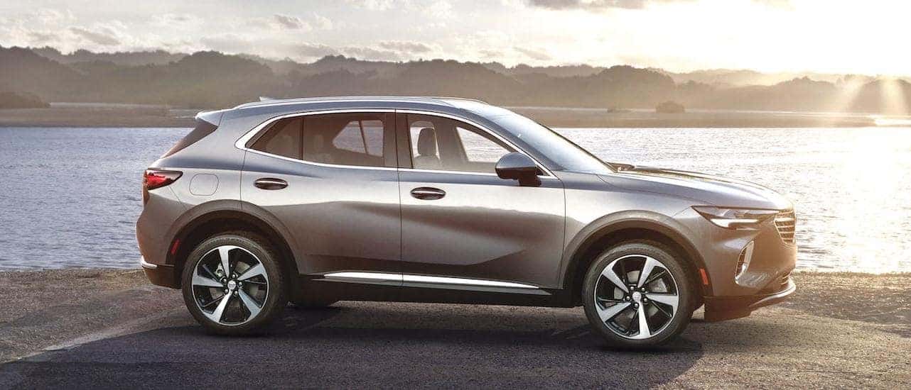 A silver 2021 Buick Envision is shown from the side while parked in front of a river.
