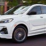 A white 2021 Buick Encore GX is driving on a city street after leaving an Atlanta Buick dealer.