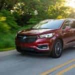 A red 2019 Buick Regal Sportback is shown driving down a tree lined road.
