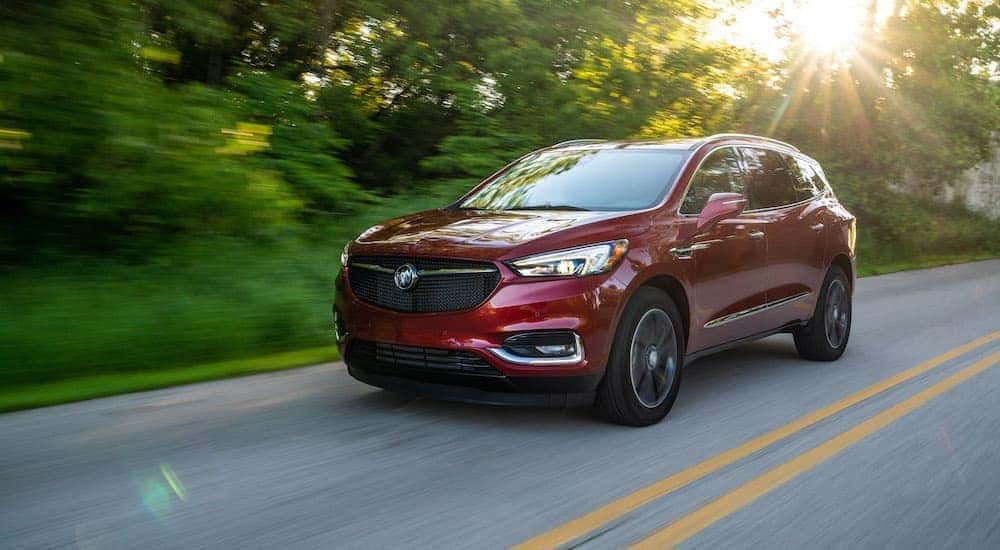 A red 2019 Buick Regal Sportback is shown driving down a tree lined road.