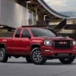 A popular used truck in Atlanta, a red 2018 GMC Sierra 1500 All Terrain, is parked in front of a building.