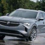 A grey 2021 Buick Envision is driving through a puddle after leaving a Buick GMC dealership near me.