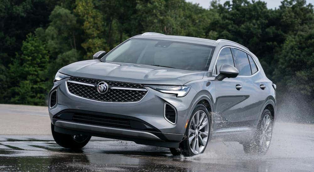 A grey 2021 Buick Envision is driving through a puddle after leaving a Buick GMC dealership near me.