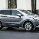 A gray 2019 Buick Envision is shown from the side driving past a blurred building.
