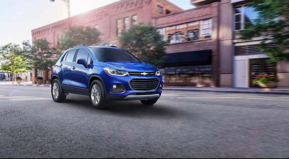 A blue 2017 Chevy Trax is driving on a city street.