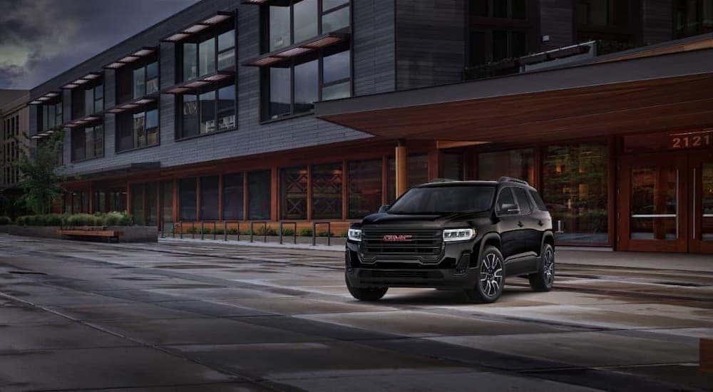 A popular GMC lease, a black 2021 GMC Acadia, is parked in front of a modern building.