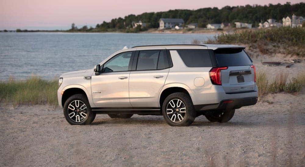 A white 2021 GMC Yukon AT4 is shown from the side parked on a beach.