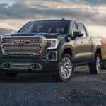 A dark grey 2019 GMC Sierra is parked at a mountain lookout at sunset.