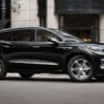 A black 2021 Buick Enclave is driving through a city after leaving the Buick dealership.