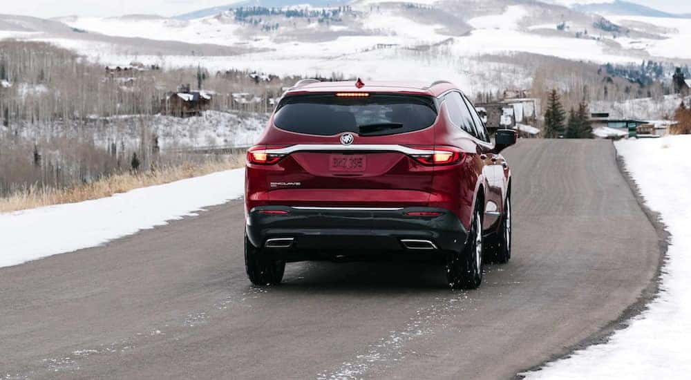 A red 2021 Buick Enclave is shown driving in winter.
