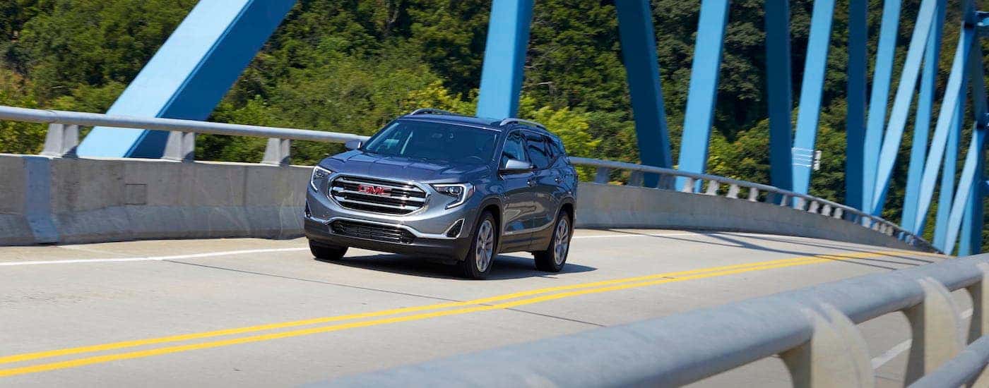 A gray 2018 GMC Terrain is shown driving down an empty bridge.