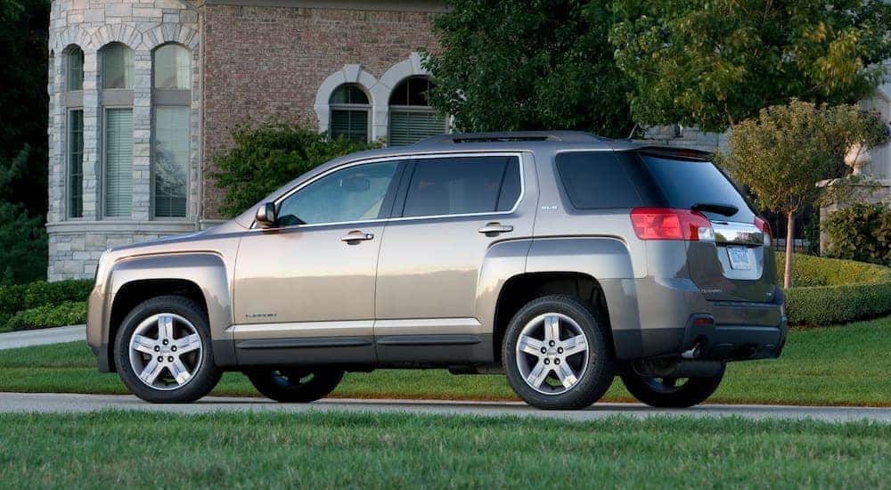 A tan 2013 GMC Terrain SLE is parked outside of a house after leaving a used GMC Terrain dealer.