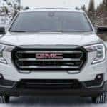 A white 2022 GMC Terrain is shown from the front driving down a snowy road.