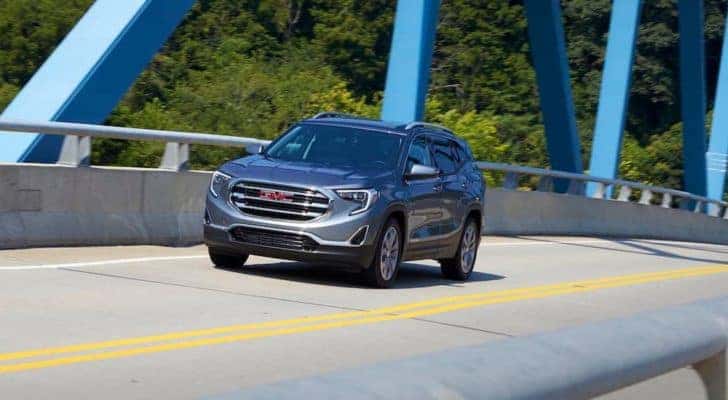 A grey 2018 GMC Terrain is shown driving over a bridge after leaving a used GMC SUV dealer.