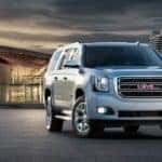 A silver 2016 GMC Yukon XL is shown parked in front of a modern building after leaving a used SUV dealer in Atlanta.