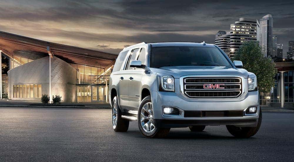 A silver 2016 GMC Yukon XL is shown parked in front of a modern building after leaving a used SUV dealer in Atlanta.