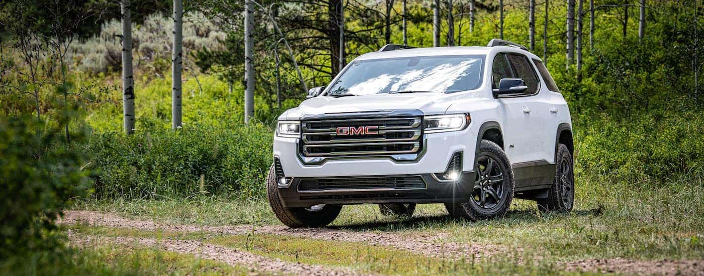 A white 2020 GMC Acadia AT4 is shown in a field.