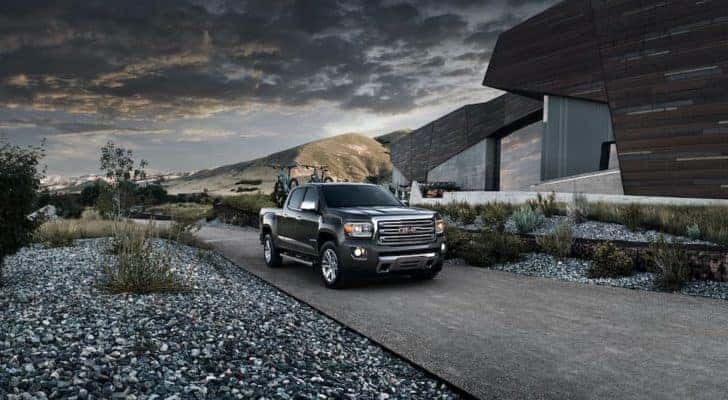 A dark grey 2015 GMC Canyon Crew Cab SLT is parked in front of a modern house after leaving an Atlanta used truck dealership.