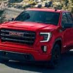 A red 2021 GMC Sierra 1500 Elevation is shown driving down the road after leaving an Atlanta used truck dealership.