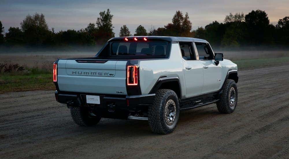 A white 2021 GMC Hummer EV Pickup is shown from the rear on a dirt path after leaving a new truck dealership in Atlanta.