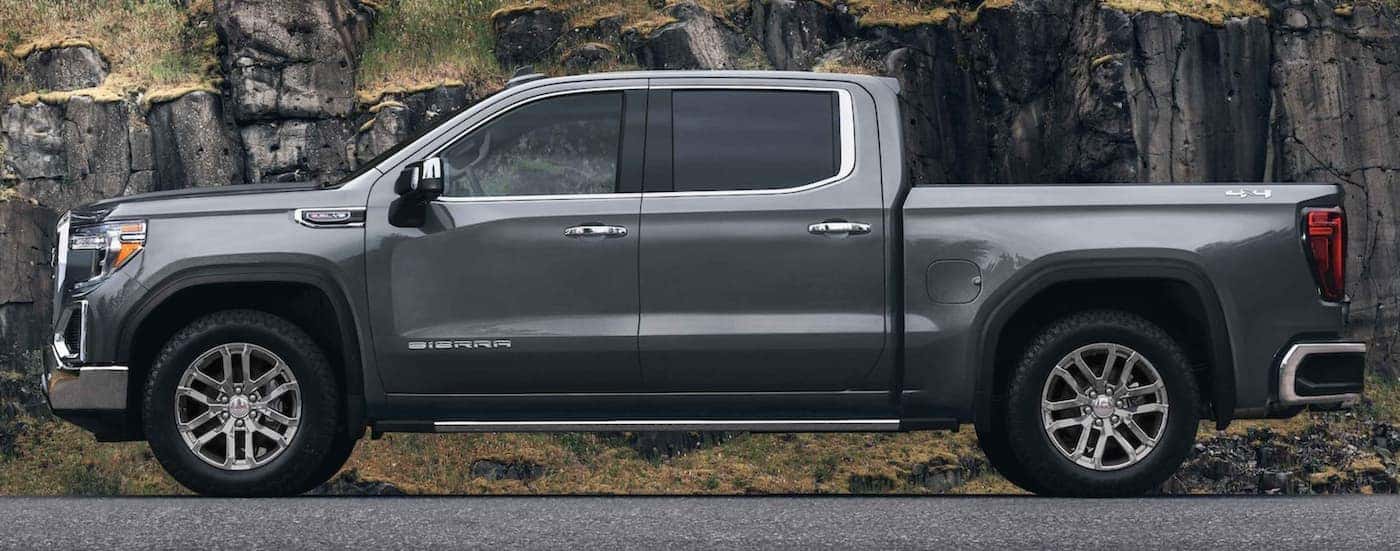 A grey 2021 GMC Sierra 1500 is shown from the side in front of a rock wall after leaving a new truck dealership in Atlanta.