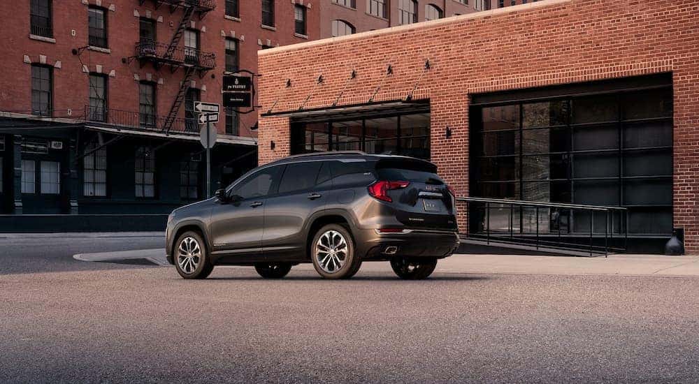 A grey 2018 GMC Terrain SLT is shown from the side parked outside of a brick building.