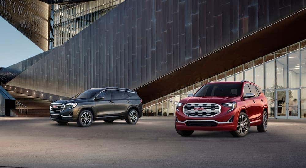 A grey 2018 GMC Terrain SLT is shown parked next to a red 2018 GMC Terrain Denali.