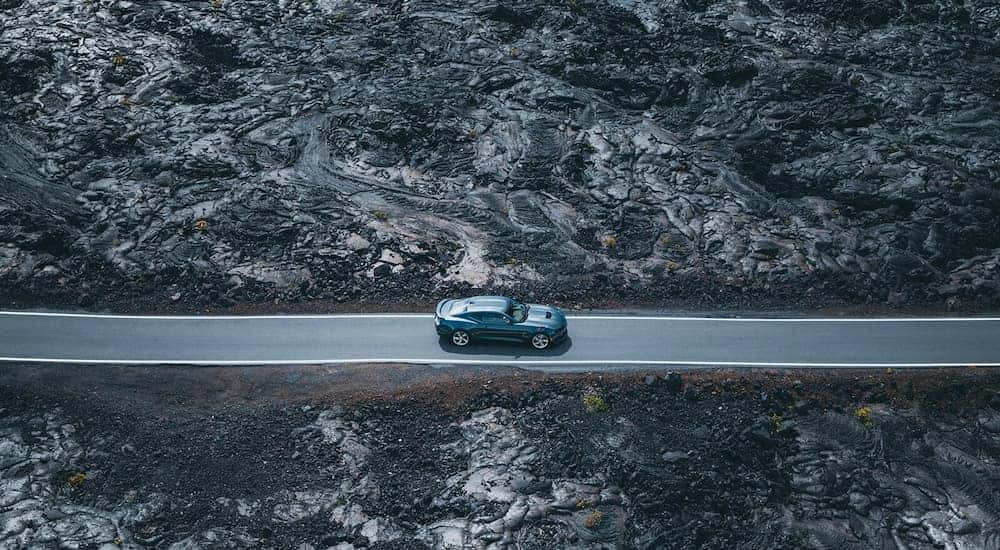 A blue 2020 Chevy Camaro SS is shown driving down an empty road.