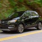 A black 2022 Buick Encore is shown driving down a two lane road.