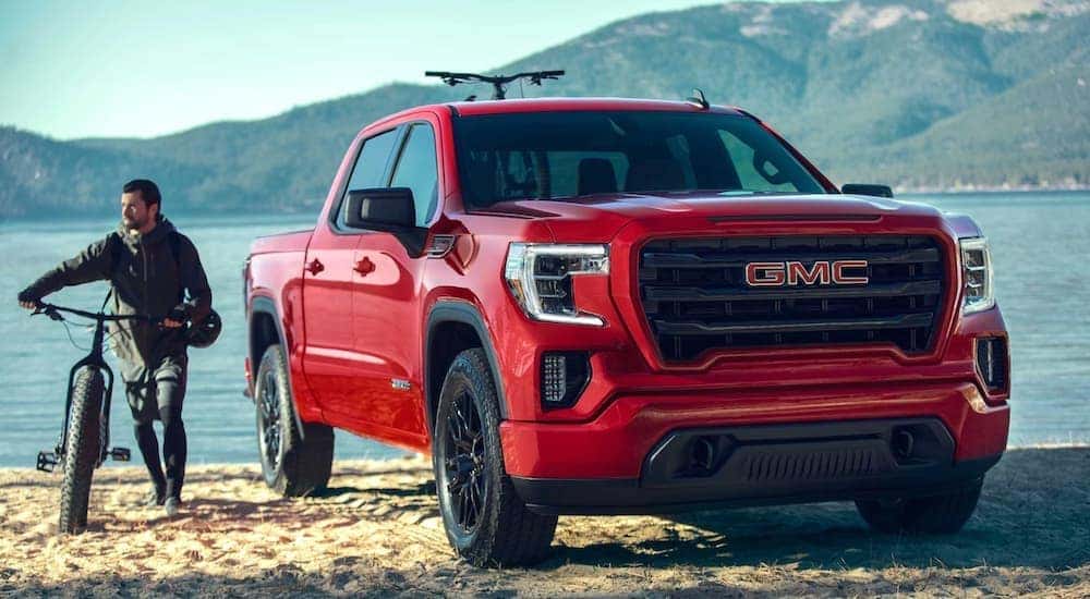 A red 2020 GMC Sierra 1500 is shown from the front parked near a lake.