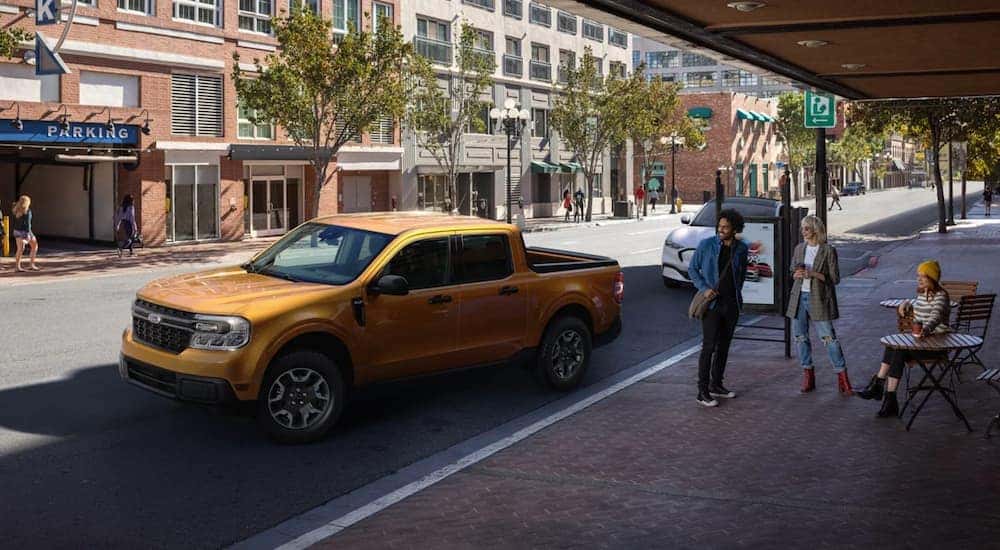 An orange 2022 Ford Maverick is shown from the side parked on a city street.
