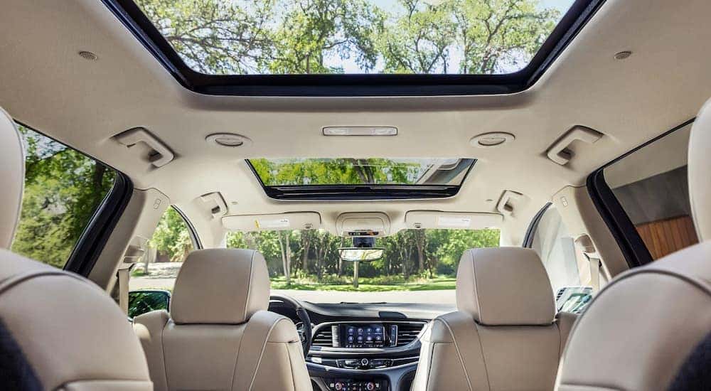 The tan and black interior of a 2022 Buick Enclave shows the front seats, moonroof, and center console.