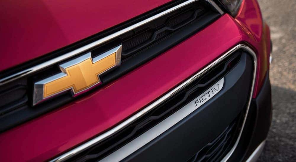 A close up of the logo and grille of a red 2020 Chevy Spark is shown at a used Chevy dealership in Atlanta.
