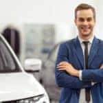 A salesman is shown standing next to a white SUV ready to help you sell your car.