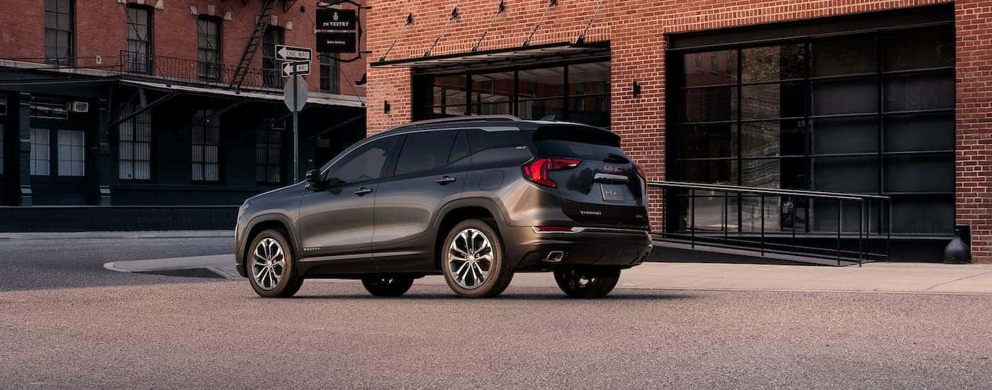 A grey 2018 GMC Terrain SLT is shown parked in front of a brick building.