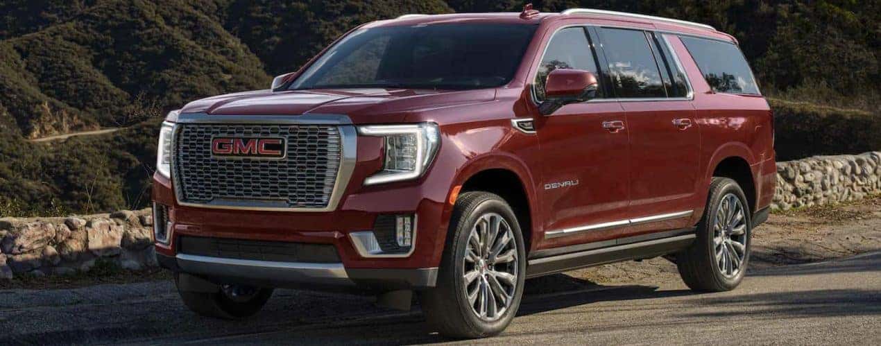 A maroon 2022 GMC Yukon Denali is shown from the side parked on the side of a road.