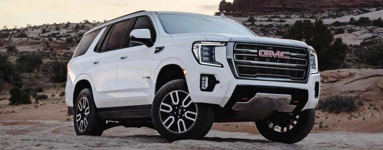 A white 2022 GMC Yukon AT4 is shown from the front parked in the desert.