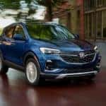 A blue 2020 Buick Encore GX is shown from the front driving on an open road after leaving a Certified Pre-Owned Buick dealer.