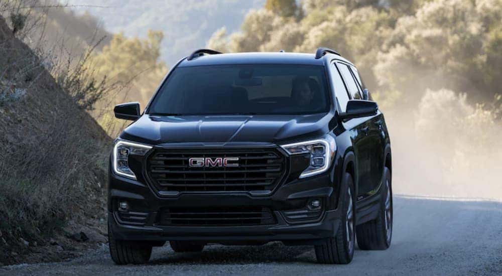 A black 2022 GMC Terrain is shown from the front driving on a dirt road.