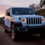 A white 2019 Jeep Wrangler is shown driving on an open road.
