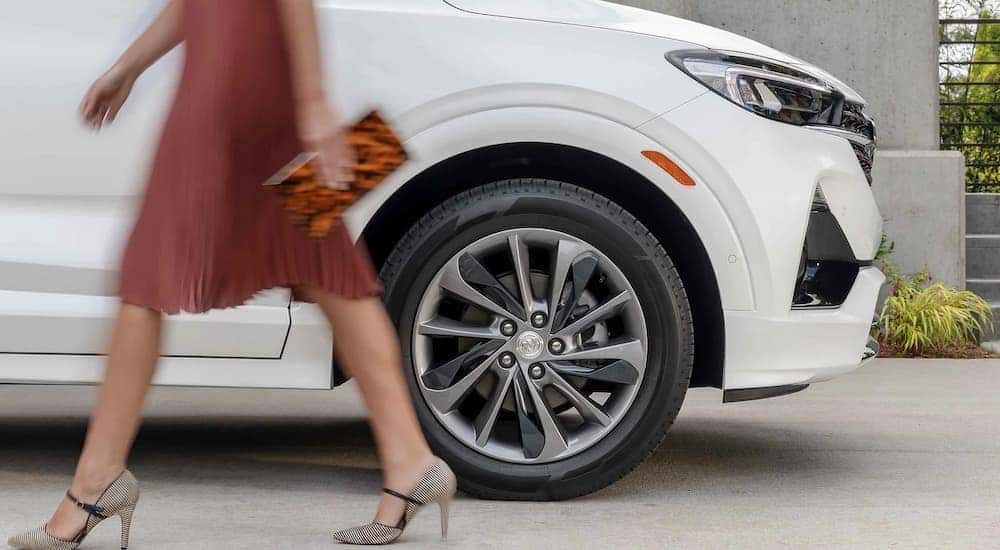 A woman is shown walking past a white 2022 Buick Encore GX sport after visiting a Johns Creek Buick dealer.
