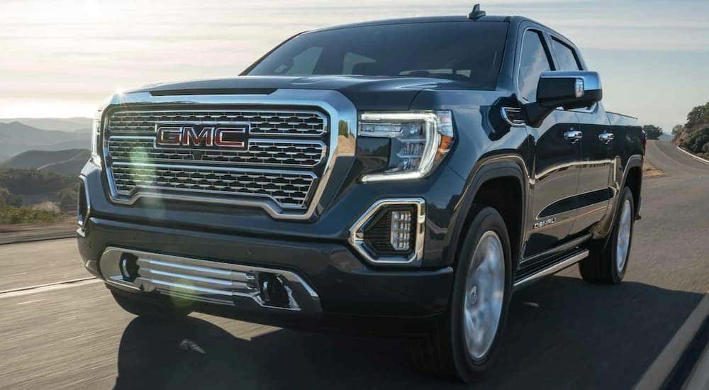 A grey 2020 GMC Sierra 1500 Denali is shown from the front at an angle while it drives down the road.
