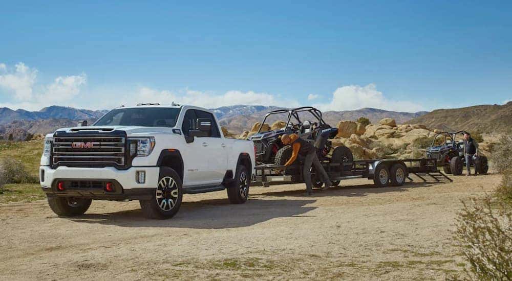 A 2022 GMC Sierra 2500HD is shown from the front at an angle while unloading UTV's after leaving a Used GMC 2500 truck dealer.